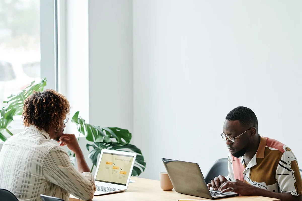 Two people working on separate laptops