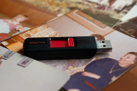 USB flash drive resting on older printed photographs