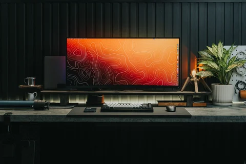 Beleuchteter Computerarbeitsplatz vor einer dunklen Wand