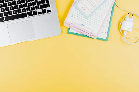 Laptop and power adapter on a yellow surface