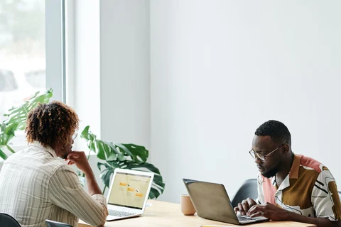 Two people working on separate laptops
