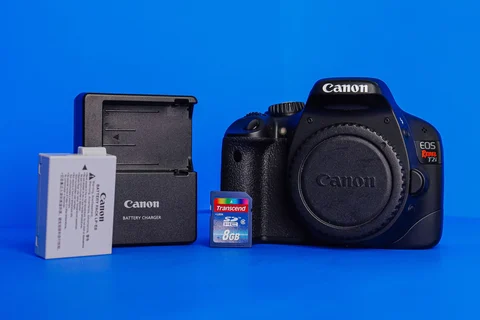 Camera, memory card and battery on a blue surface