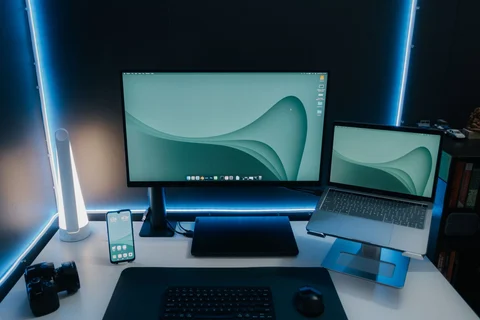 Monitor and laptop on an illuminated desk